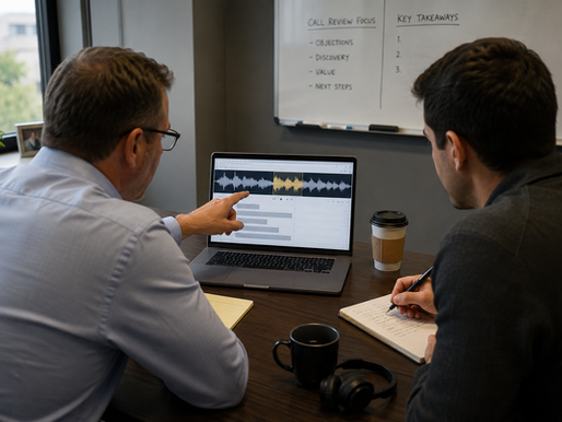 Sales manager and sales representative reviewing a recorded sales call together on a laptop during a coaching session.
