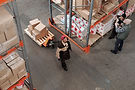 3 people in a storehouse carrying boxes