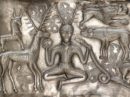 Ancient Celtic depiction of Cernunnos, the horned god, seated cross-legged with stag antlers, holding a torc and a serpent, surrounded by animals.