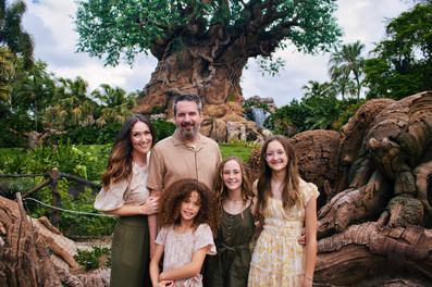 Family wearing coordinating neutral tones in front of the tree of life at Disney's Animal Kingdom Orlando, Florida