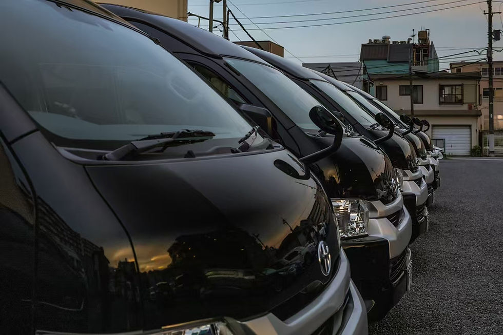 A close-up, angled view of a row of black Toyota HiAce van parked in a Tokyo lot.