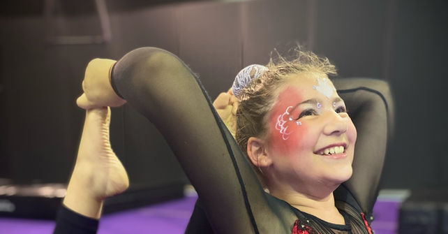 Young girl in costume arched back smiling on purple mat