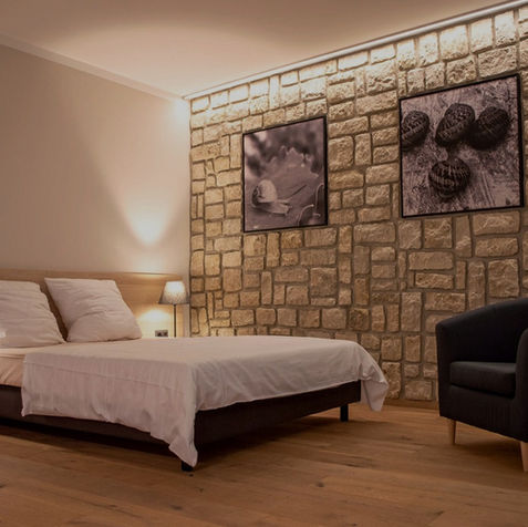 Doppelzimmer mit Natursteinwand, Holzboden und stilvoller Beleuchtung