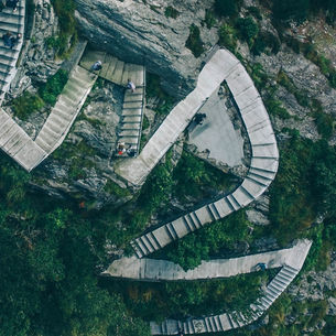 Aerial view of a winding stone stairway built into a rocky cliff, representing the twists, adjustments, and continued progress of recovery.