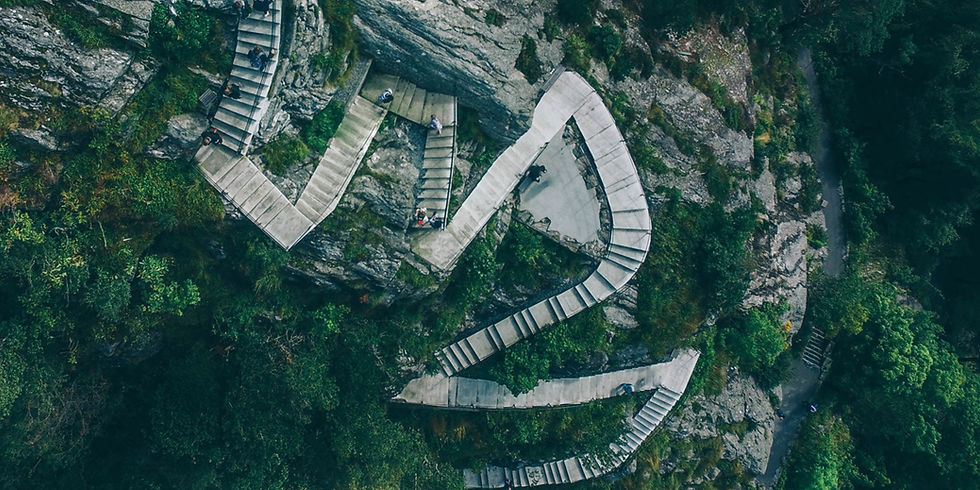 Aerial view of a winding stone stairway built into a rocky cliff, representing the twists, adjustments, and continued progress of recovery.
