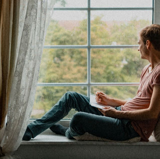 man sitting alone window natural light