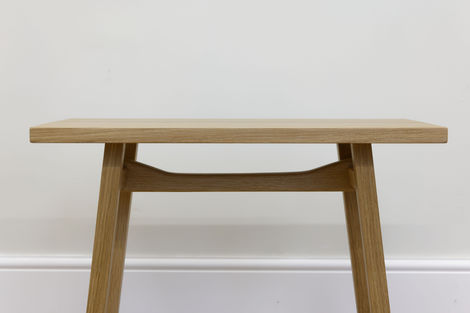 a wooden bench is against a white wall