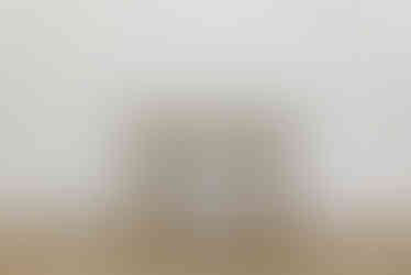 a small wooden table sits on a wooden floor in front of a white wall
