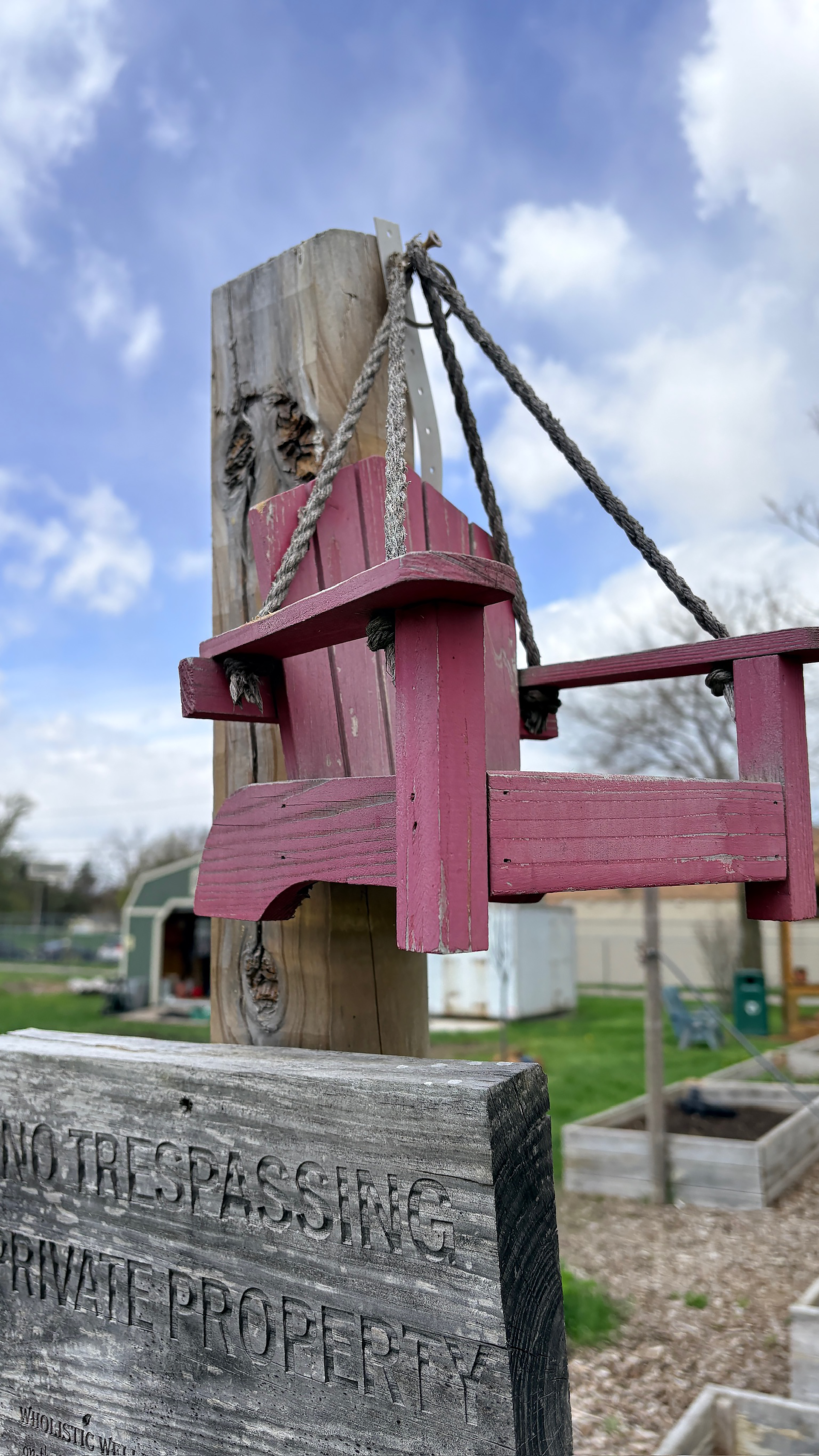 tiny adironrack chair hanging from a garden post