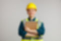 smiling-young-female-construction-worker-wearing-safety-helmet-safety-vest-hugging-notepad