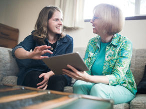 A young adult helping a senior with technology