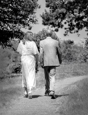 A black and white image of the bride and groom walking down a path from the church