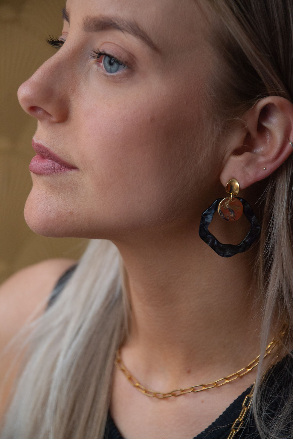 model draagt gekleurde bijzondere oorbellen donkerblauw goud