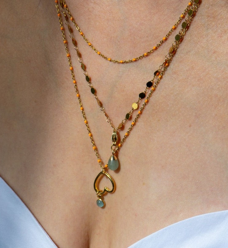 Model draagt gouden ketting met edelsteen geboortesteen Aquamarijn de geboortesteen van de maand maart.