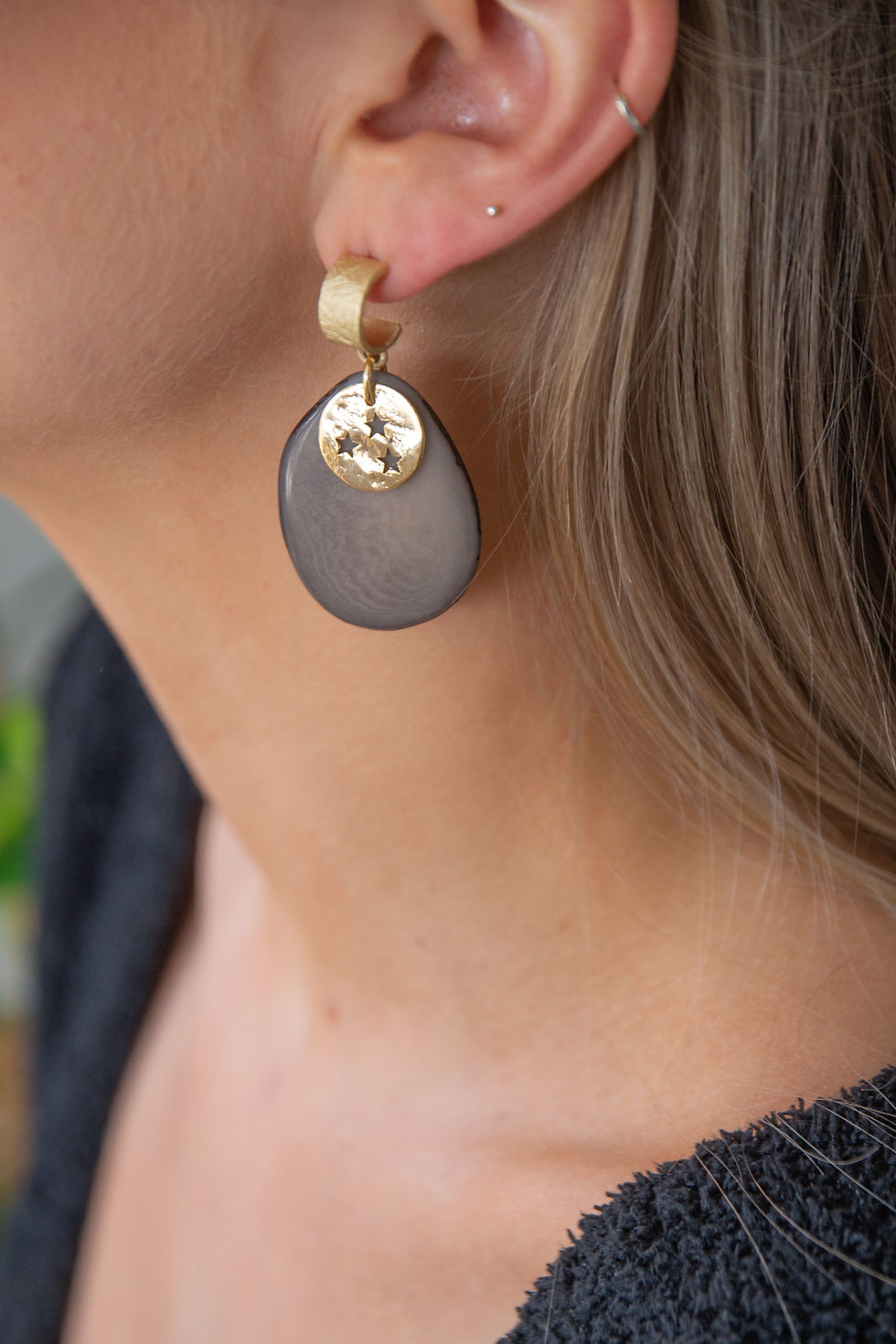 Model draagt bijzondere gekleurde oorbellen gemaakt van natuurlijke materialen