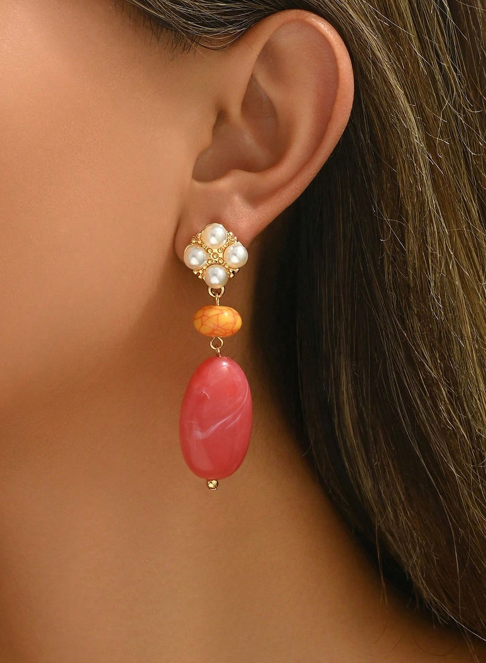 gekleurde statement oorbellen in roze en geel kleur met parel details van world'd finest modelfoto