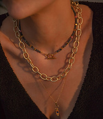 model draagt kettingen van world's finest in lagen