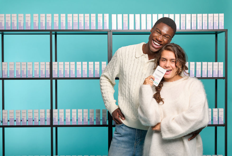 Two people smiling in front of product shelves.