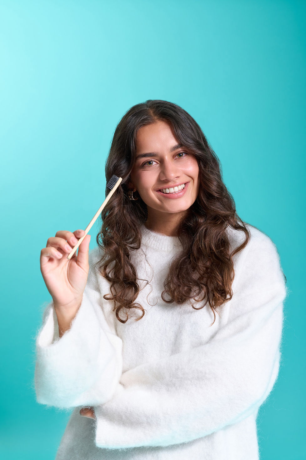 Smiling person holding a stick against blue background.