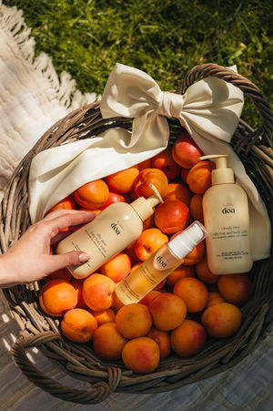 a person is holding a little doa product in front of a basket of apricots