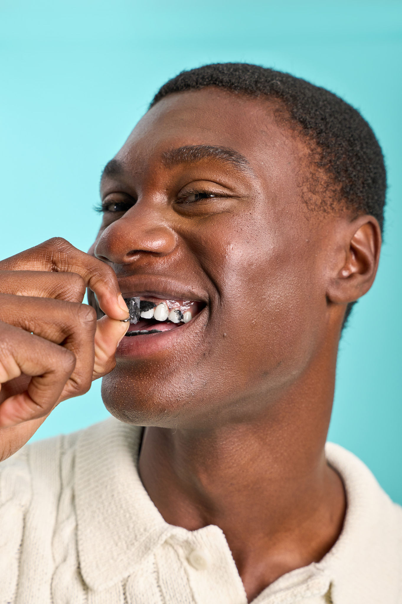 Person smiling while inserting dental aligner.