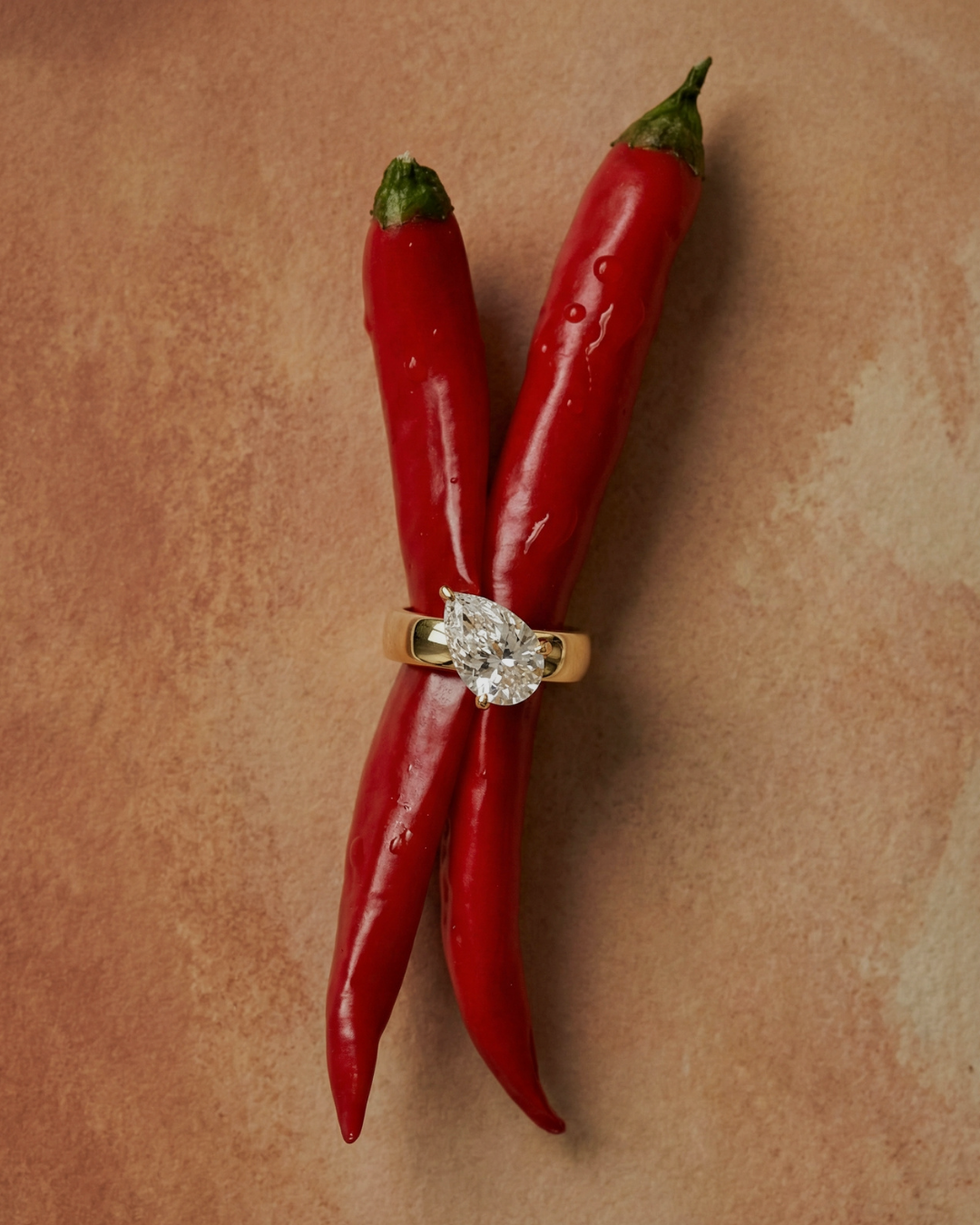 Three red chili peppers with a diamond ring.