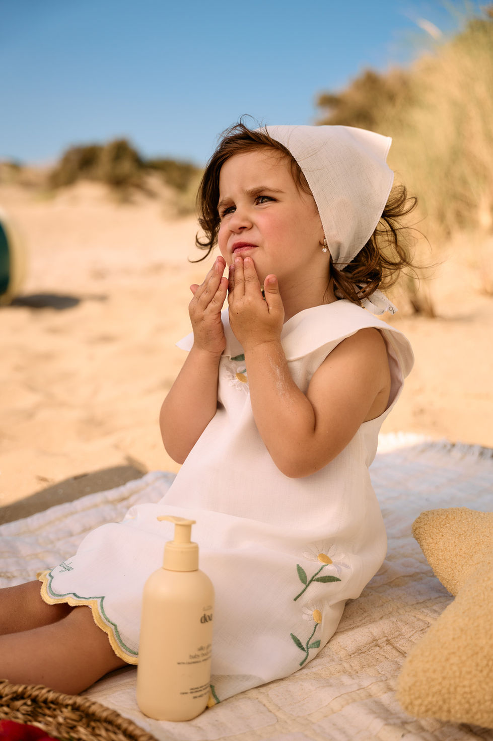 Child applying lotion on the beach.
