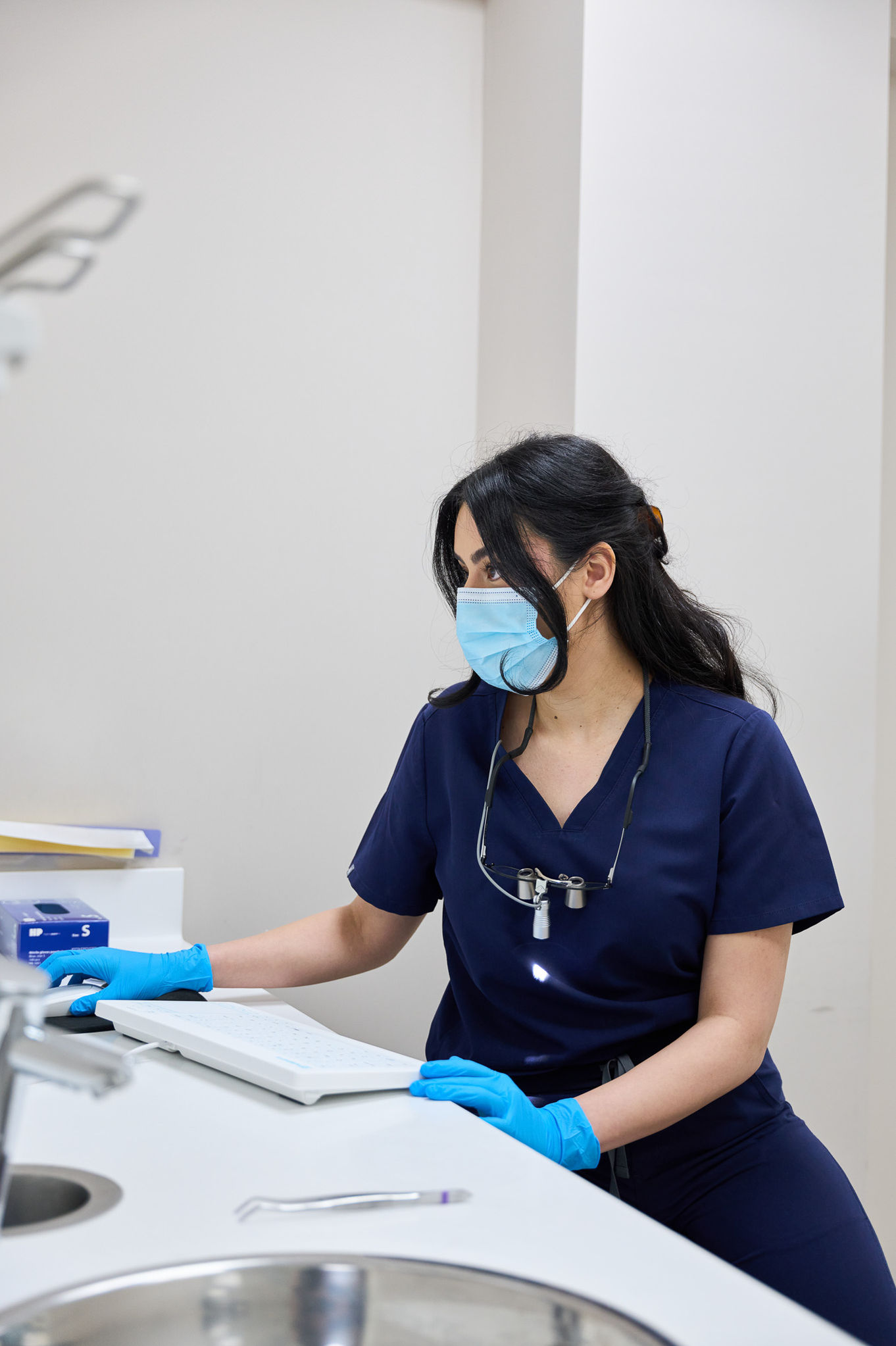 Healthcare professional working at a desk, wearing a mask.