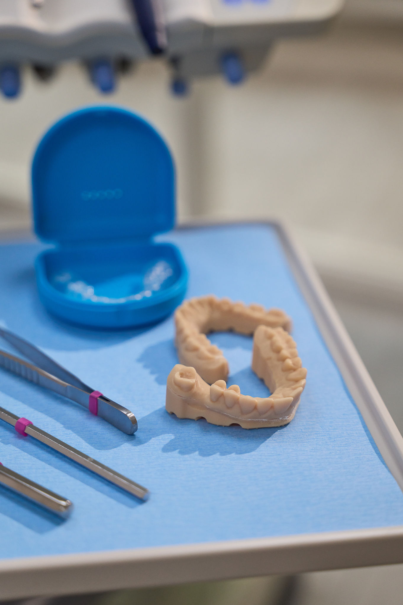 Dental tools and mold on a blue surface.
