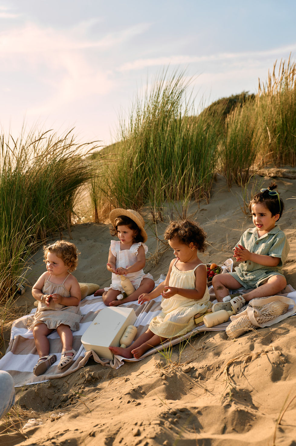 Four children having a picnic on a sandy hill.