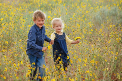 Boy and girl holding hands and running in a field of sunflowers.