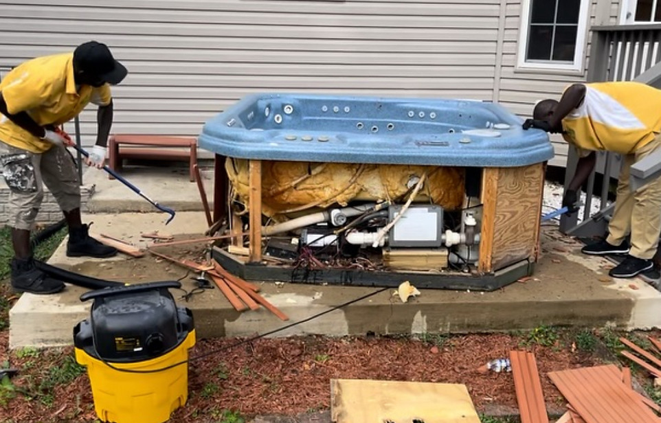 Professional crew dismantling and removing an outdoor hot tub for safe hauling and disposal