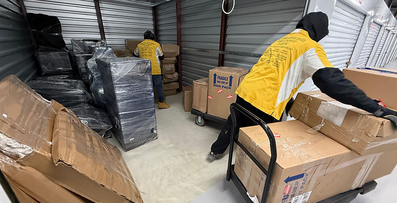 Junkman Removal & Disposal Services crew clearing boxes and wrapped furniture inside a storage unit during a cleanout in Maryland.
