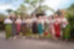 A group of guests at Firefly Retreat in Bali share a moment of mindful connection. Dressed in vibrant, traditional colorful sarongs, they stand with their palms pressed together in a respectful Sembah or Namaste gesture. Their warm smiles reflect the peaceful energy of the island.