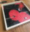 Wooden tray with red poppies, black background, and a glass