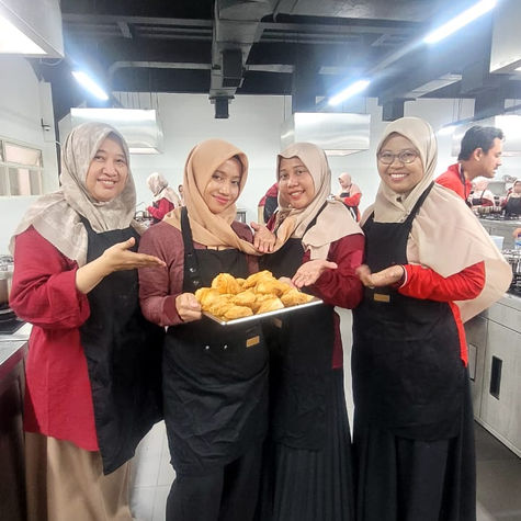 Teachers participating in a hands-on culinary training session, preparing dishes as part of a professional development program focused on entrepreneurship education.
