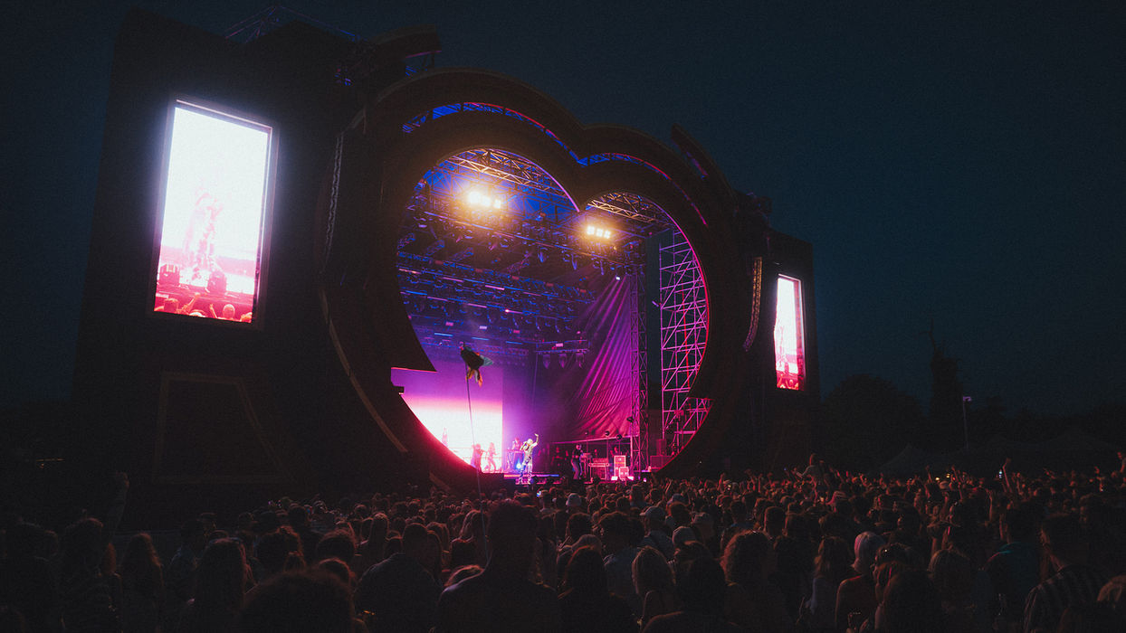 Love Saves stage at night, crowd silhouetted by blue-purple-red ombre lighting from the stage