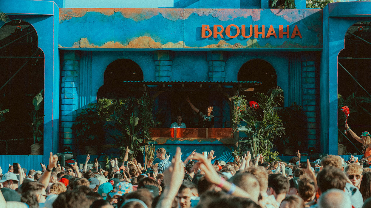 The Brouhaha stage, blue and weathered frontage in a vaguely Morrocan style, decked with green plants, surrounded by a crowd.