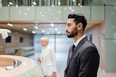 side view of bi-racial security man near blurred businesswoman checking in at hotel recept