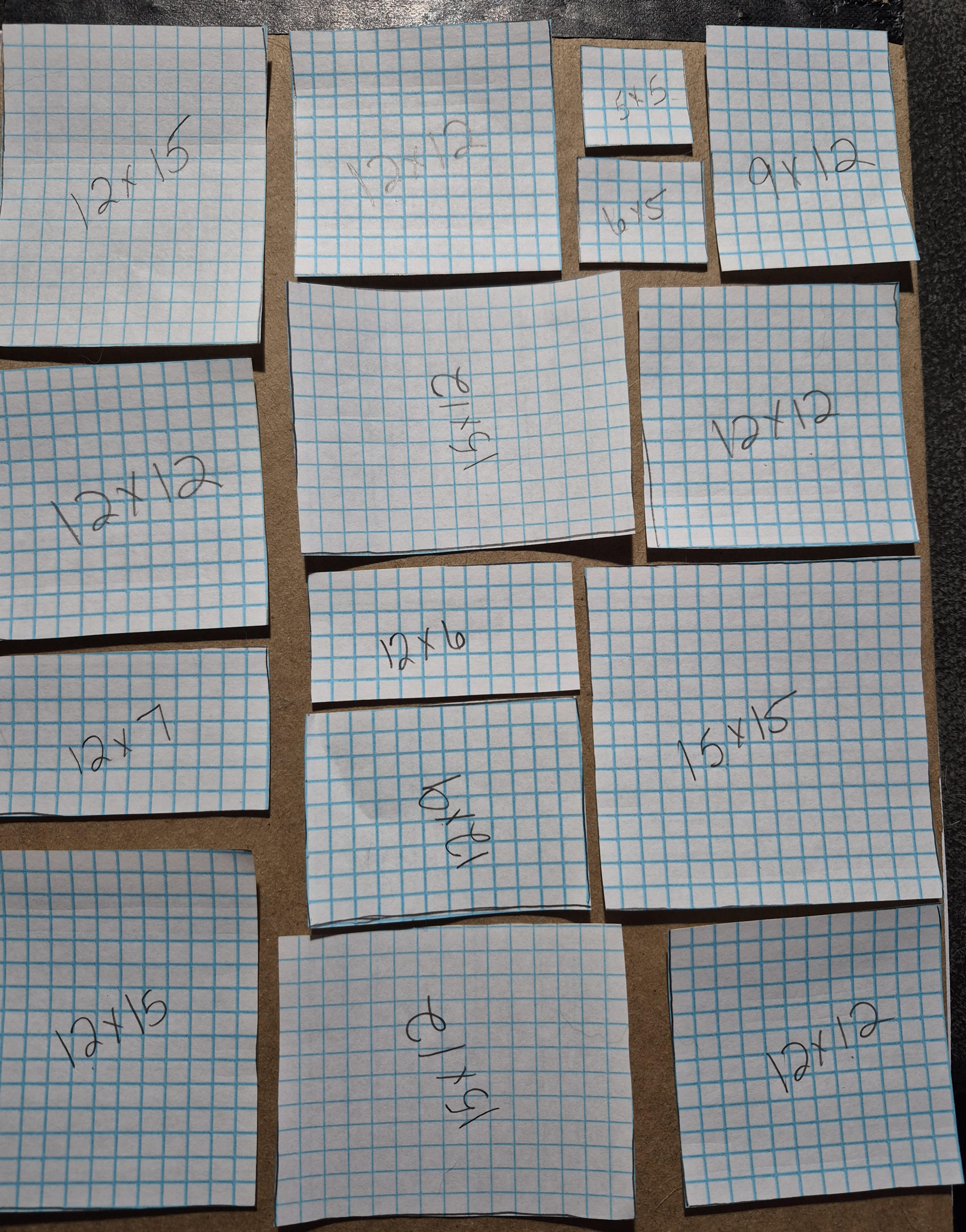 Paper templates in assorted rectangular sizes arranged to plan the layout of a custom T-shirt quilt.
