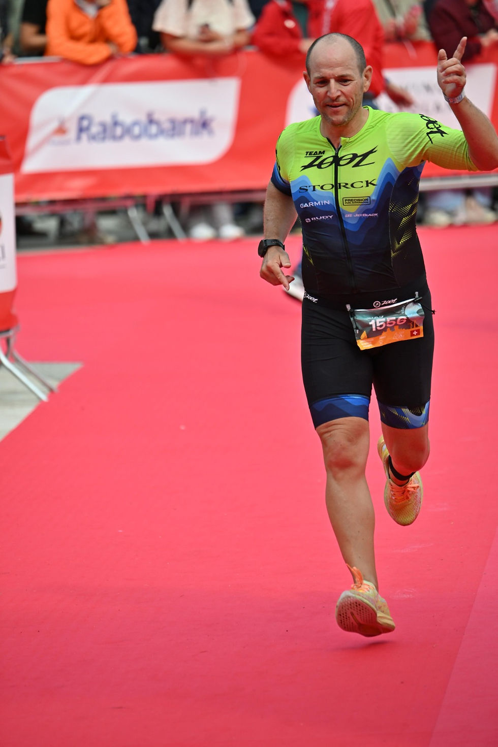 Patrick Schlup läuft glücklich und mit erhobener, winkender Hand über den roten Teppich beim Zieleinlauf der Challenge Almere-Amsterdam.