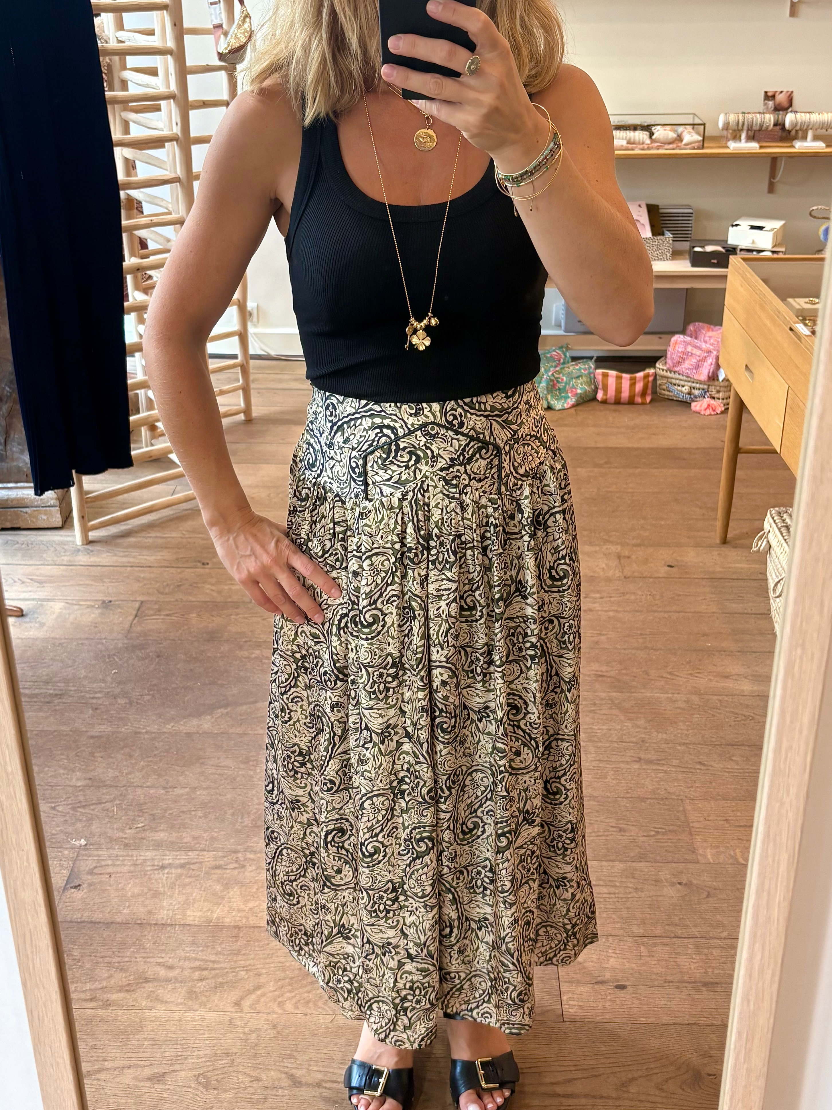 Femme en jupe imprimée noire et kaki devant miroir