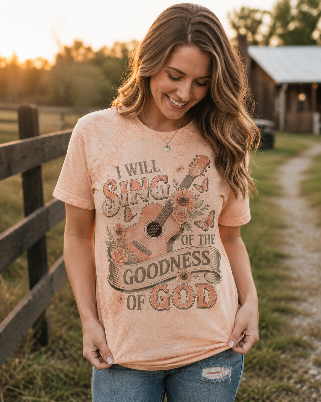 Peach Christian graphic tee featuring a floral guitar design and “I Will Sing of the Goodness of God” message.