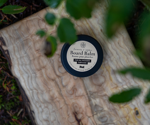 A board balm tin sitting on a quilted maple charcuterie board in the Discovery Islands