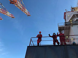 Three masked seafarers on ship with cran