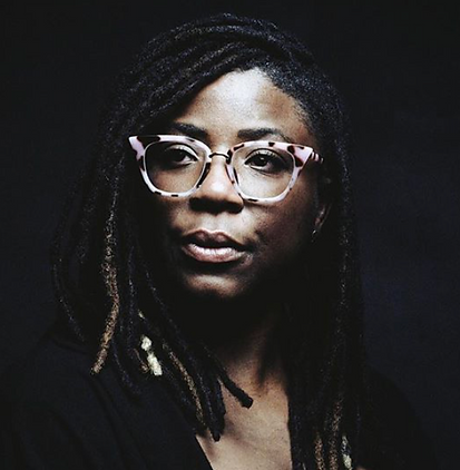 head shot of Faidat. She's wearing pink cat eye glasses, has long dreads and is looking off to the side.