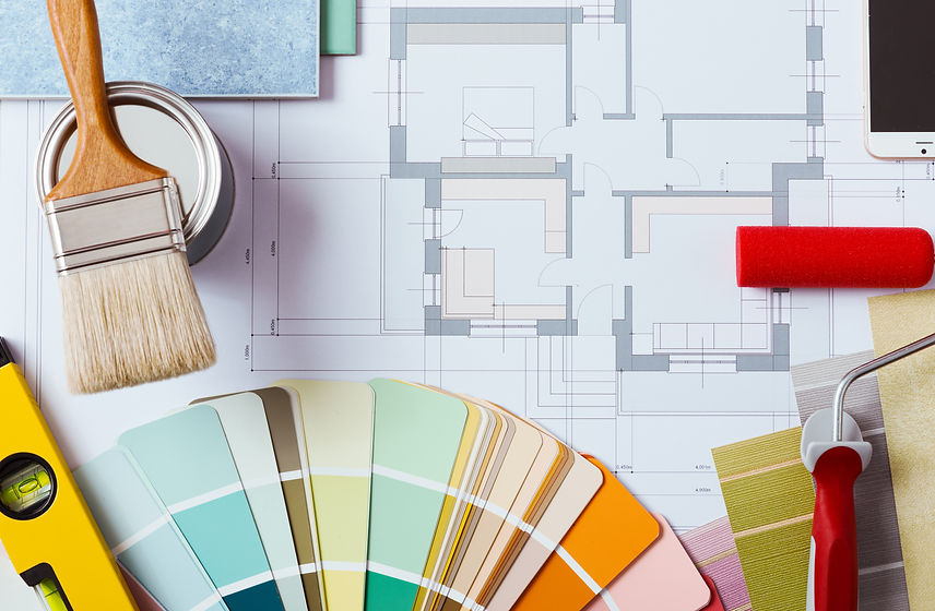 Painter and decorator work table with house project, color swatches, painting roller, brus