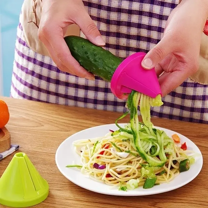 Manual vegetable slicer peeling cucumber over pasta