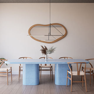 A contemporary dining room featuring a blue dining table (colour WKD) surrounded by wooden chairs, styled with a minimalist mirror and natural decor elements.