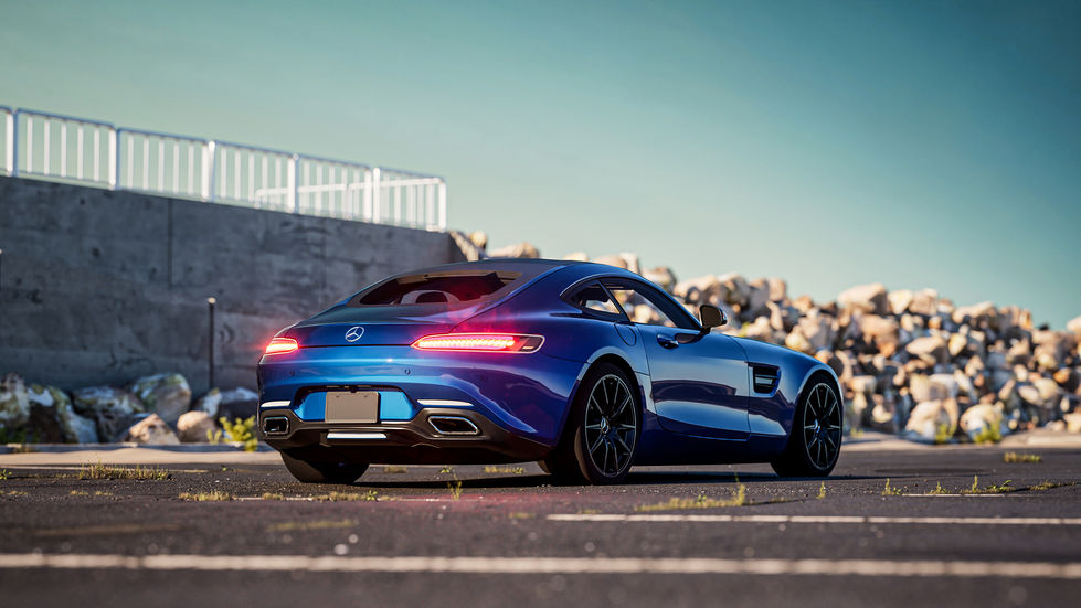 Mercedes-AMG GT in vibrant blue parked in an empty lot during a picturesque sunset, showcasing its sleek design and performance-oriented aesthetic.